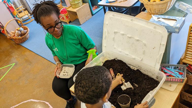 Chastity Bey helps a child plant seeds during a school program